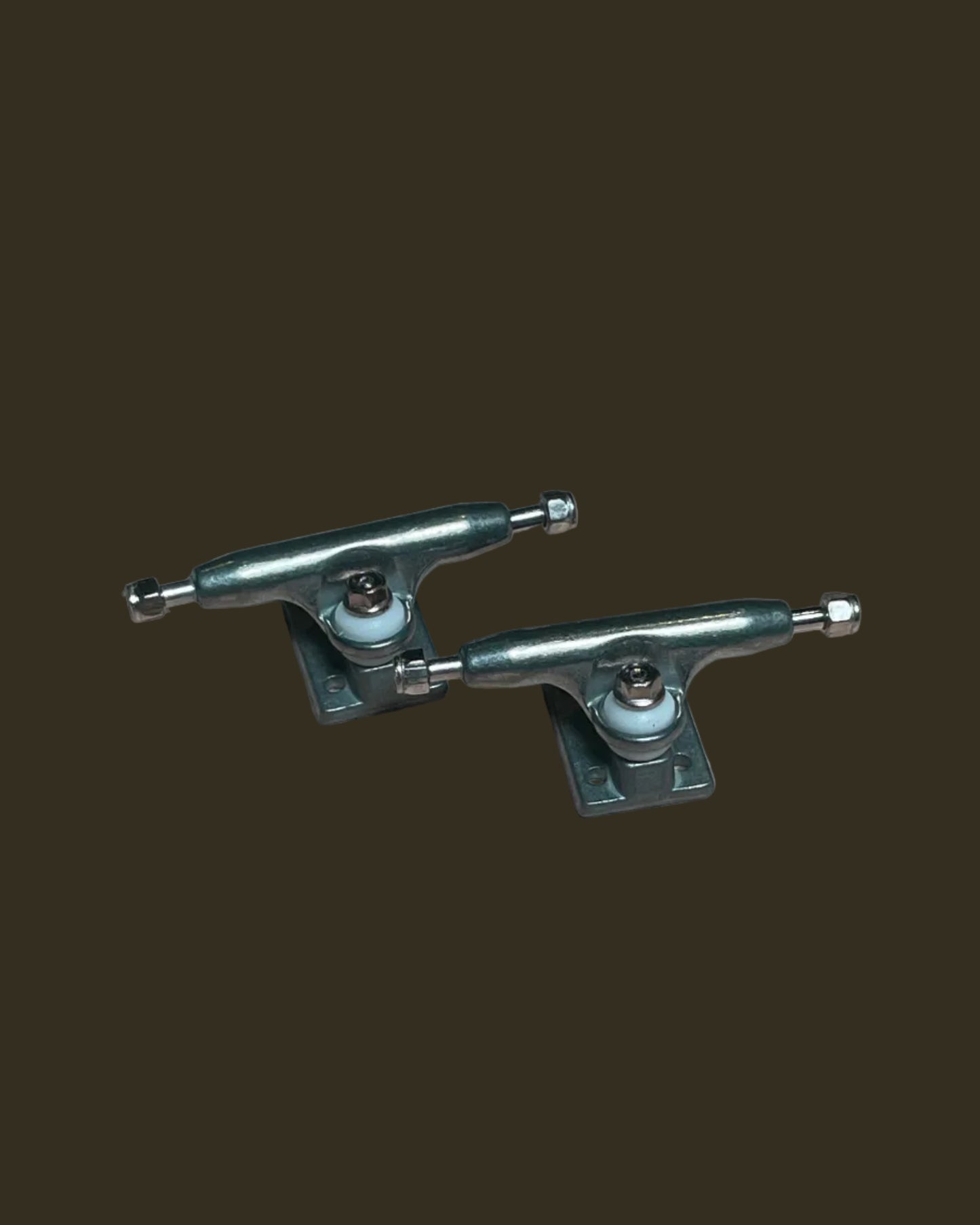 Two metal skateboard trucks on a cardboard surface